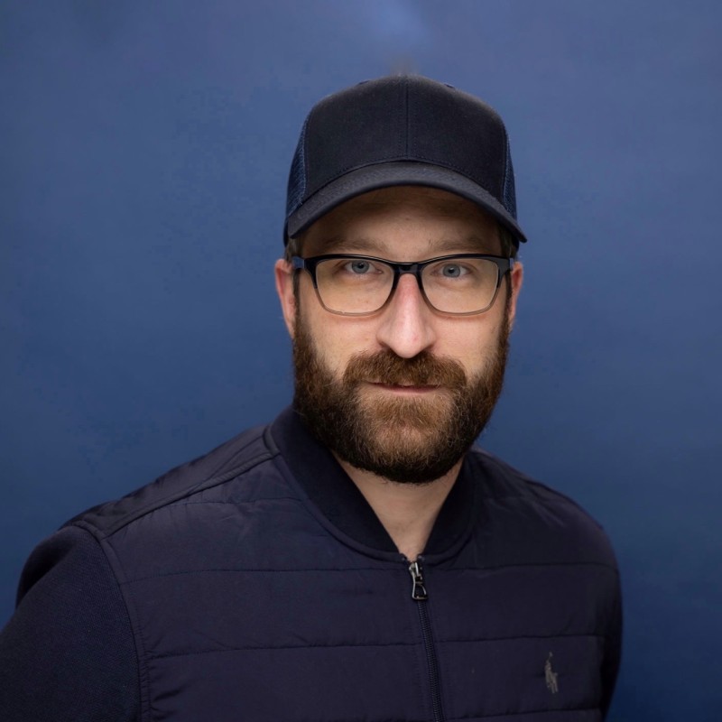 Pierre Bergamin, co-founder of Cotrugli — wearing a cap and glasses against a navy background.